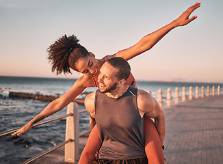 Image showing Beach, fitness and couple piggyback at sunset happy for summer holiday, vacation and quality time on weekend. Love, dating and black man and woman relax after exercise, workout and training by ocean