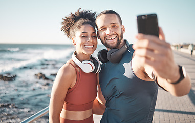 Image showing Fitness, couple and phone with smile for selfie, running exercise or workout in the outdoors. Happy man and woman smiling in happiness looking at smartphone for photo after run by the ocean coast