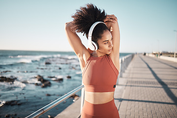 Image showing Beach, headphones and woman stretching for a fitness exercise, running or training for a race or marathon. Health, sports and female athlete doing an arm warm up before a cardio workout by the ocean.