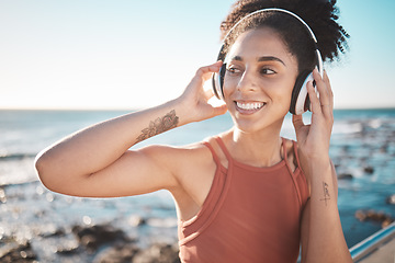 Image showing Music, thinking and fitness with a sports black woman by the sea during her running workout at the sea. Exercise, training and radio with a female runner listening to audio by the ocean in summer