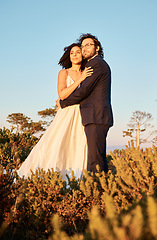 Image showing Interracial couple, love and wedding at sunset, hug and happy for romance and relationship in nature. Marriage, bride and groom hug at outdoor ceremony and sweet on blue sky background space