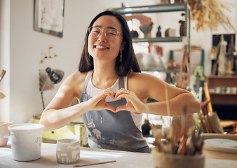 Image showing Happy woman, portrait or heart hand gesture in pottery studio, Asian small business or creative ceramic workshop. Smile, clay or art mud worker in love, support or trust vote of startup store success