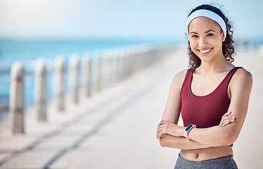 Image showing Happy woman, portrait and fitness with arms crossed at beach promenade for exercise, wellness and mockup in Miami. Female athlete, smile and standing at seaside for workout, summer training or sports