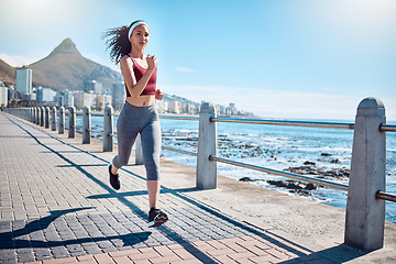 Image showing Woman running at ocean promenade for fitness, energy and strong body in Cape Town. Female runner, sports person and athlete at seaside for marathon, cardio exercise and healthy summer workout in sun