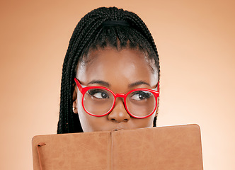 Image showing Black woman, notebook and hide face in studio for thinking, glasses or planning schedule for small business online. Young african entrepreneur, book or ideas for goal, vision or notes by background