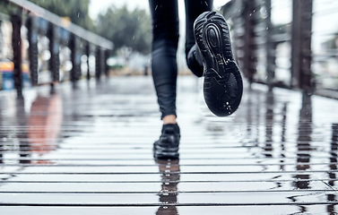 Image showing Runner training in the rain, person doing workout and outdoor cardio for marathon race in Seattle road. Shoes splash water in puddle, step on wet ground and legs moving fast for fitness exercise