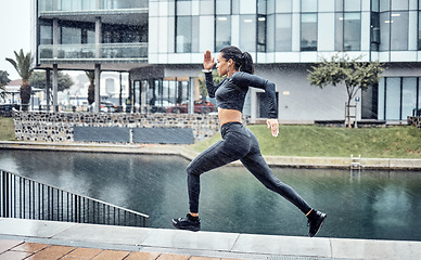 Image showing Run, rain and black woman with fitness, workout and training for marathon, wellness and healthy lifestyle. Wet, African American female athlete and runner outdoor, practice and balance for energy