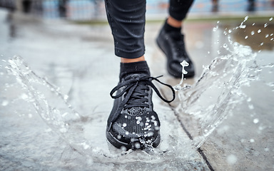 Image showing Shoes of person running in the rain, feet splash water in puddle and outdoor cardio in Seattle road. Runner training for marathon, step on wet ground and legs moving fast for fitness exercise