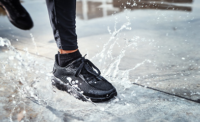 Image showing Feet splash water in street, person running in the rain and shoes in puddle of Seattle road for outdoor cardio. Runner training for marathon, step on wet ground and moving fast for fitness exercise