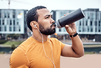 Image showing Fitness, athlete and man drinking water in the city after running for exercise or marathon training. Sports, hydration and male runner enjoying a drink after a intense cardio sport workout in town.