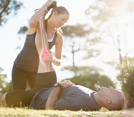 Image showing Fitness, couple and helping or stretching leg for healthcare, pain or ache after running workout in nature. Happy woman holding man legs for stretch to sooth painful knee or area from cardio exercise