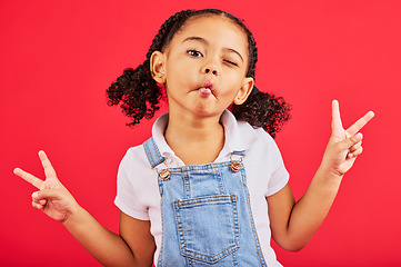 Image showing Happy, peace sign and kiss with portrait of girl for summer, happiness and funny face. Meme, fashion and smile with child and hand sign for youth, comedy and positive in red background studio