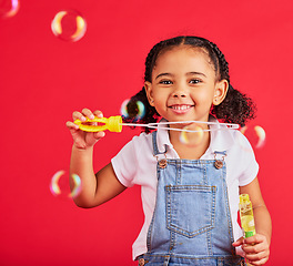 Image showing Little girl, portrait or bubbles playing on isolated red background in hand eye coordination, kids activity or fun game. Smile, happy or child and soap wand, studio toy or breathing development skill