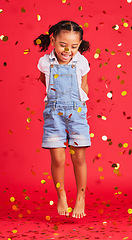 Image showing Young girl, kid jump with confetti, happiness and party with celebration, gold and glitter isolated against red background. Fun, youth and happy child at event, celebrate and birthday in studio