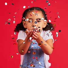 Image showing Young girl, child blowing confetti with party and celebration, silver and glitter isolated against red background. Fun, youth and kid at event, celebrate and birthday in studio with decoration