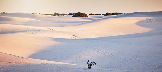 Image showing Desert, motorcycle and athlete doing a sport jump for outdoor competition, training or exercise. Extreme sports, sand dunes and man riding motorbike doing skill, trick or challenge for race in Dubai.