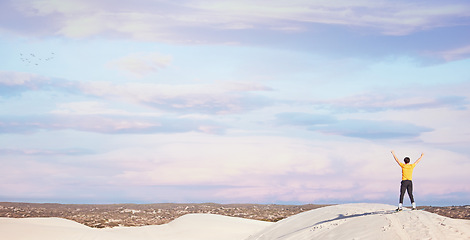 Image showing Freedom, power and back of a man in the desert for adventure, travel success and holiday in Dubai. Free, peace and carefree traveller at the dunes on a vacation with victory, win and sunset view