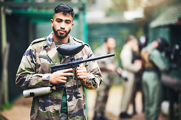 Image showing Paintball game and portrait of a man with gun and safety uniform for outdoor shooting battle. Assertive and young indian guy in camouflage clothing ready for shooter sport and activity.