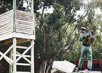 Image showing Paintball, gun or man in a shooting game playing with fast action on a fun battlefield on holiday. Mission focused, military or player aiming with weapons gear for survival in an outdoor competition