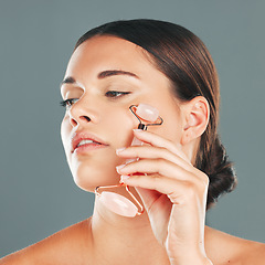 Image showing Face massage closeup with roller, woman and skincare, beauty and healthy skin isolated on studio background. Natural cosmetics, glow and rose quartz makeup tools in hand, manicure and cosmetic care
