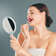 Image showing Red lipstick, mirror and woman face with smile happy with cosmetics and makeup brush. Mouth, female and beauty model looking at reflection with cosmetic tool with studio background and lips product