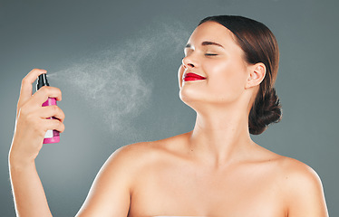 Image showing Cosmetic, face spray and woman in a studio for a makeup, skincare and natural facial routine. Self care, wellness and female model with a facial cosmetics treatment isolated by a gray background.