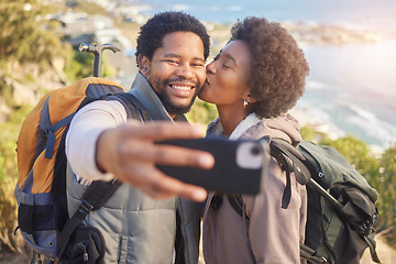 Image showing Selfie, kiss and black couple hiking on mountain for fitness, fun and romantic walk in natural landscape. Romance, man and woman taking self portrait in nature with smile in mountains on island trip