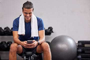 Image showing Fitness, phone or man on social media to relax at gym in training, workout or exercise resting on a break. Tired, happy or healthy sports athlete typing text on a bench and exercising for body goals