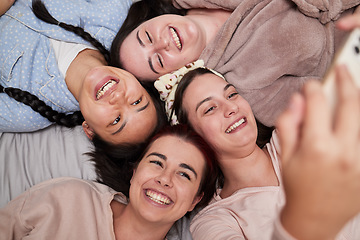 Image showing Selfie, happy and friends lying in a circle while at a fun friendship sleepover at a house. Happiness, smile and women taking a picture for memories while relaxing, laughing and bonding together.