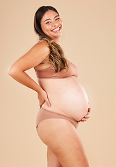 Image showing Portrait, pregnant and stomach with a model woman in studio on a beige background for motherhood. Baby, beauty and wellness with an attractive young mother in underwear for pregnancy or body health