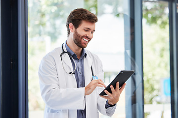 Image showing Doctor, man and tablet for research at hospital for social media app, email and networking by window. Happy medic, communication or typing medical advice for help, consulting or chat on web at clinic