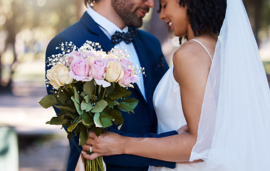 Image showing Wedding, couple and hug with flower bouquet outdoor at marriage celebration event for bride and groom. Happy interracial man and woman at ceremony with trust, partnership and together for commitment