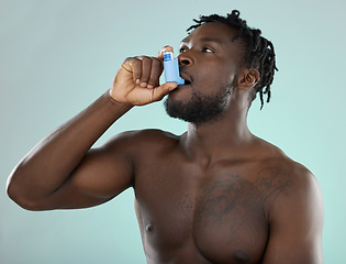 Image showing Asthma pump, sick and man in a studio with bronchitis, illness or medical chest problems. Inhaler, healthcare and African male doing a asma treatment with medication isolated by a blue background.