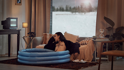 Image showing Bored, man and in home sitting in pool in the lounge in a retro home watching vintage TV with no signal. Winter, snow and hipster relaxing in the living room in a house during vacation or a holiday