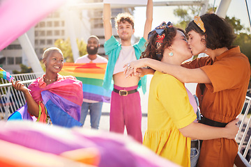 Image showing Lgbt, kiss and couple of friends in city with rainbow flag for support, queer celebration and relationship. Diversity, lgbtq community and group of people enjoy freedom, happiness and pride identity