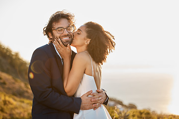 Image showing Kiss, hug and wedding bride with groom for love, care and connection together in nature. Happy, partner and bond of interracial people at outdoor marriage celebration on hill in sunset.