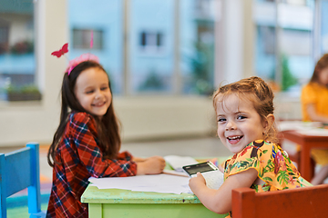 Image showing Creative kids during an art class in a daycare center or elementary school classroom drawing with female teacher.