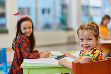 Image showing Creative kids during an art class in a daycare center or elementary school classroom drawing with female teacher.