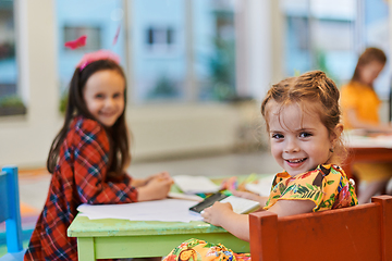 Image showing Creative kids during an art class in a daycare center or elementary school classroom drawing with female teacher.