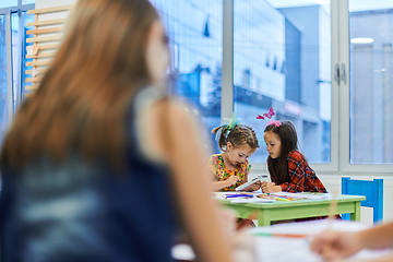 Image showing Creative kids during an art class in a daycare center or elementary school classroom drawing with female teacher.