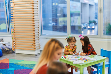 Image showing Creative kids during an art class in a daycare center or elementary school classroom drawing with female teacher.