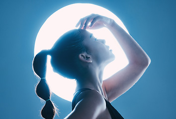 Image showing Beauty, light and profile of a model in a studio with a sensual, soft and attractive pose. Cosmetic, magical and slim woman with a mystical glow posing by a moon while isolated by a blue background.