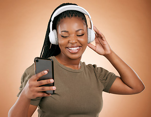 Image showing Headphones, smartphone and black woman isolated on studio background for music streaming, dance and happy. Smile of african person, hand holding phone with audio technology for student subscription