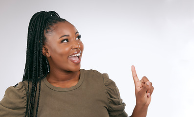 Image showing Mockup, thinking and black woman pointing at studio background, advertising space and wall. Happy female model, ideas and product placement of marketing, promotion announcement and commercial review