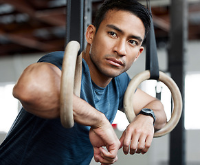 Image showing Thinking, gymnastic rings and olympics with a man gymnast hanging on equipment for workout in gym. Idea, fitness and exercise with a male athlete training in gymnastics for health or power