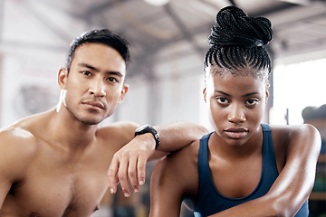 Image showing Portrait, fitness and serious with a sports couple sitting in the gym together after a workout for health. Exercise, diversity and strong with a man and woman athlete sitting in a training facility