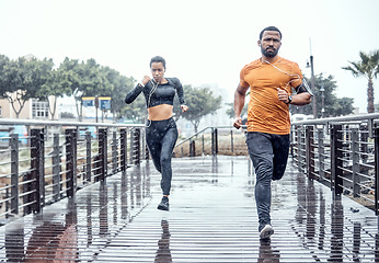 Image showing Personal trainer, rain and athletes running as exercise on a city bridge training, fitness or workout outdoors in town. People or fit friends sprint fast for wellness, cardio and health lifestyle