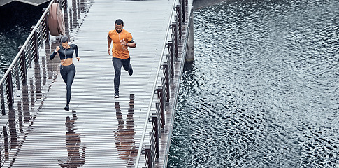 Image showing Overhead, fitness and man with woman running as exercise on city promenade training or workout outdoors in a town. Athlete, runner and fit male sprint fast for wellness, cardio and health by water