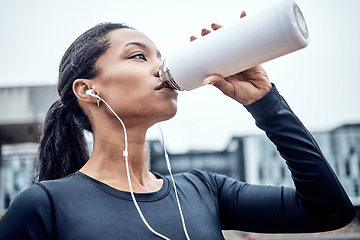 Image showing Fitness, water and black woman drinking in city for wellness, healthy body and cardio workout outdoors. Sports, motivation and girl listening to music for exercise, running and marathon training