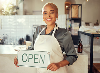 Image showing Open sign, business and black woman portrait in startup cafe, restaurant or coffee shop with smile for success. Waitress, manager or person hand holding board for welcome, services and happy career